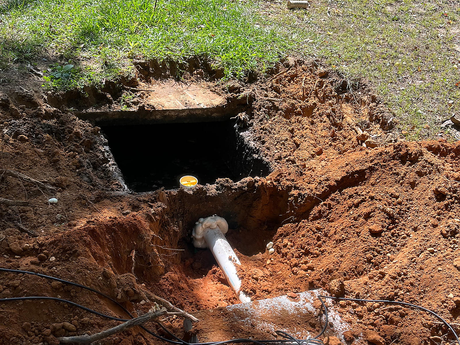 Exposed septic tank opening and white pipe in the excavated Northport yard