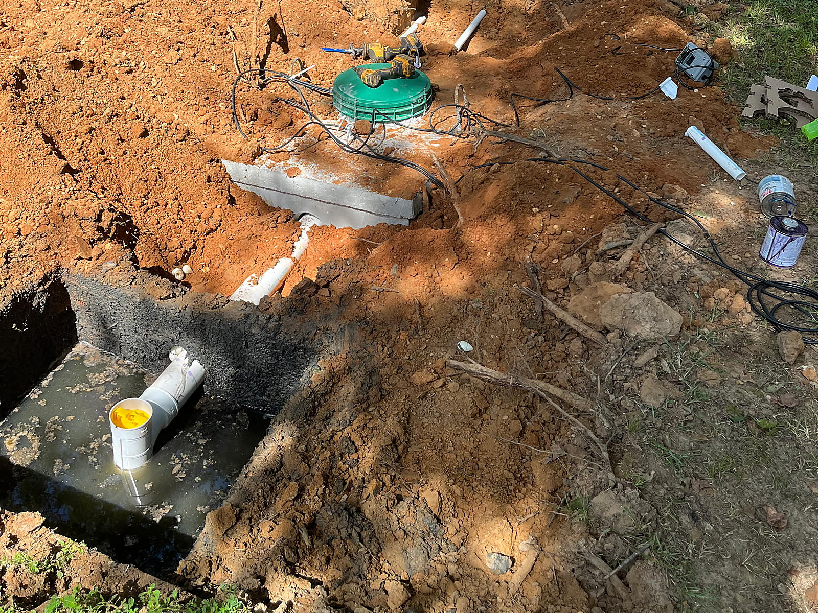 New concrete pump tank with a green access lid and pipe connection beside the existing tank