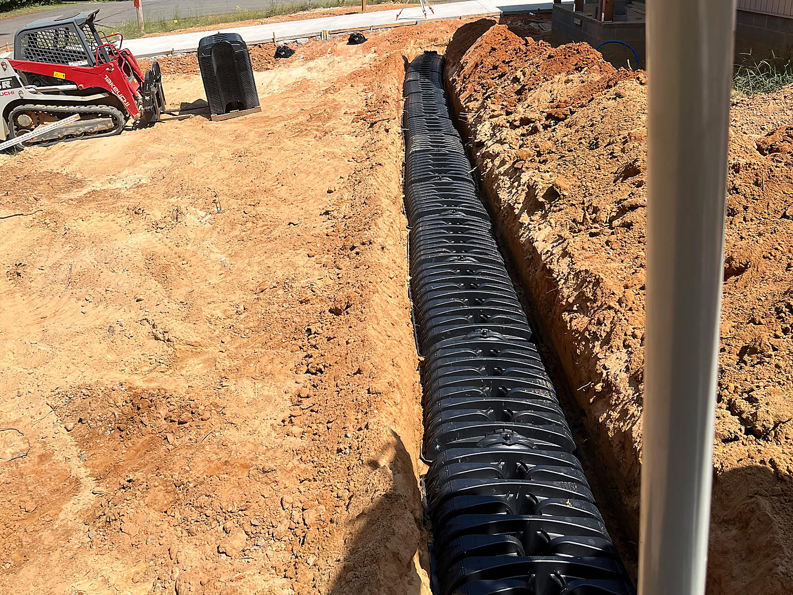 Black drainfield chambers laid in a trench beside a house at the Coker job site