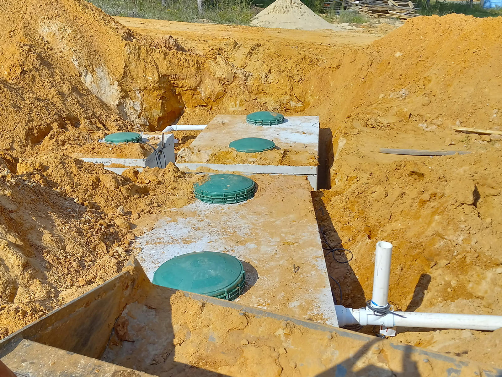 Concrete septic tanks with green access lids and connecting pipes in the Fayette excavation